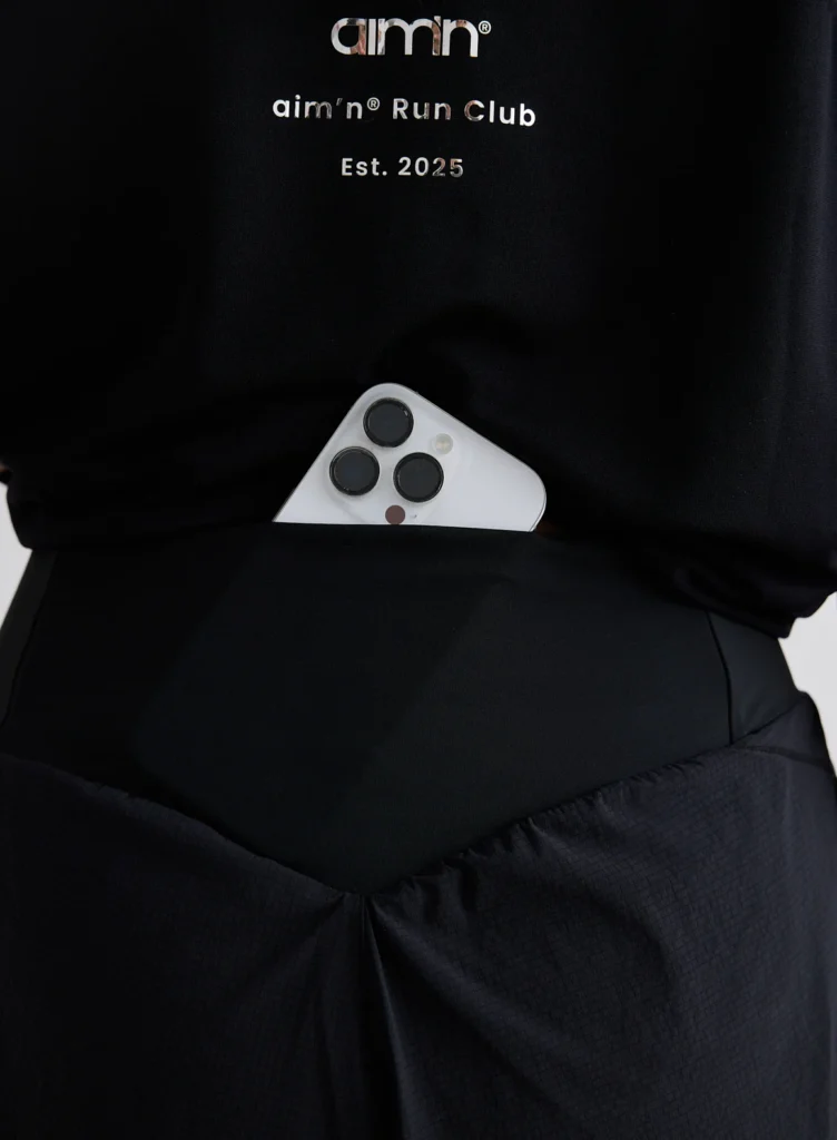 Detail van het aim'n logo en de ademende stof van de zwarte running shorts